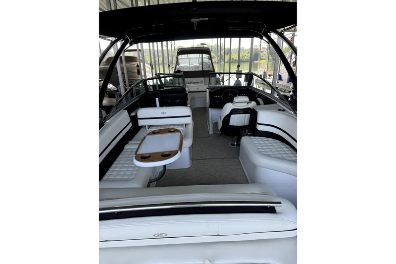 Slide: The Image of 2019 Cobalt R7 boat interior with white seating and wooden table, docked in a marina. - 5