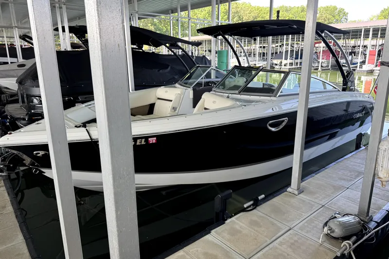 The Image of 2019 Cobalt R7 boat docked in a marina, featuring sleek black and white design. - 1