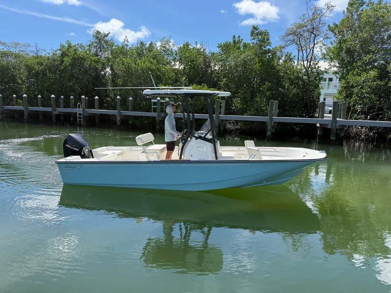Slide: The Image of A 2027 Boston Whaler 210 Montauk on calm water. It features a T-top and an outboard motor. - 6