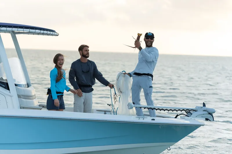 Slide: The Image of Three people stand on a boat, holding up a caught lobster. - 15