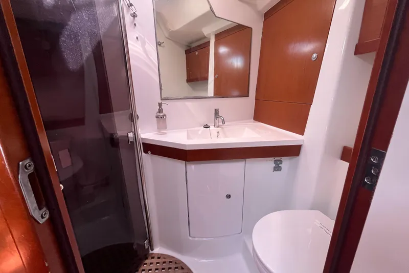 Slide: The Image of Bathroom interior of 2011 Beneteau Oceanis 54 yacht, featuring sink, mirror, and wooden cabinetry. - 38