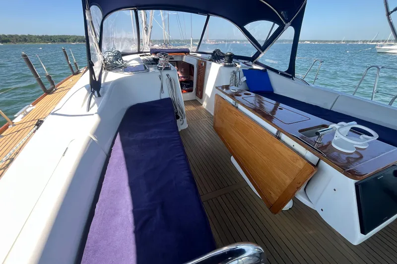 Slide: The Image of Cockpit of 2011 Beneteau Oceanis 54 sailboat with blue cushions and wooden table. - 16