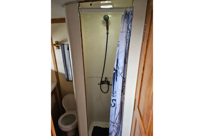 Slide: The Image of 1988 Silverton 37 Motor Yacht bathroom with shower, toilet, and nautical-themed curtain. - 27