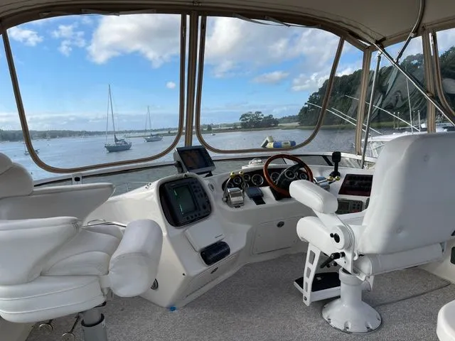 Slide: The Image of The cockpit of a 2001 Sea Ray 400 Sedan Bridge with white seats and a view of the water. - 8