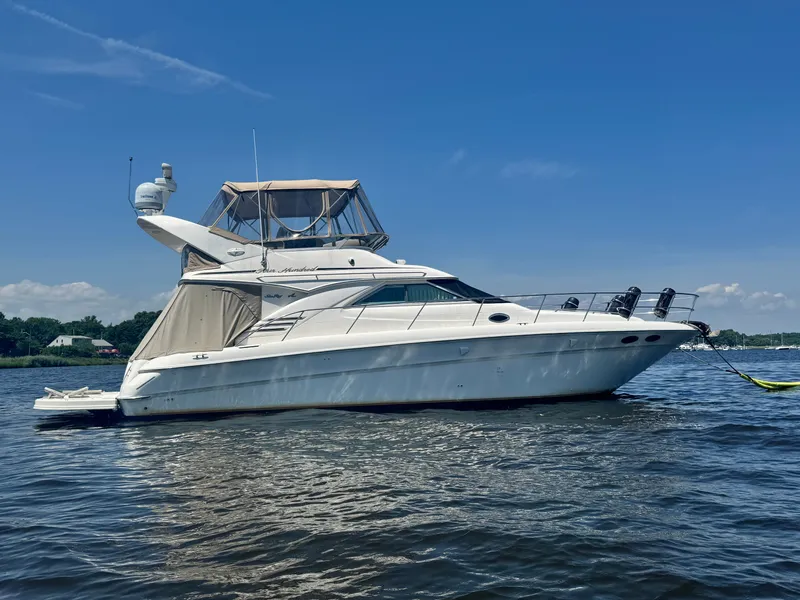 Slide: The Image of A white 2001 Sea Ray 400 Sedan Bridge floats on calm water under a blue sky. - 4