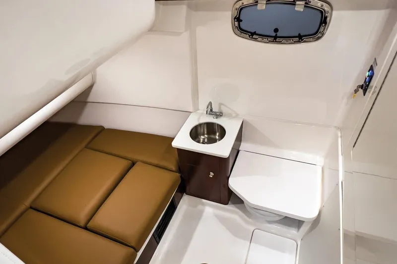 Slide: The Image of 2023 Robalo R360 Center Console cabin with sink, toilet, and cushioned seating. - 46