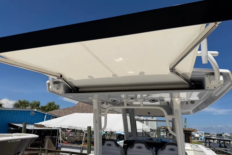 Slide: The Image of 2023 Robalo R360 Center Console boat with retractable sunshade, docked under clear blue sky. - 25