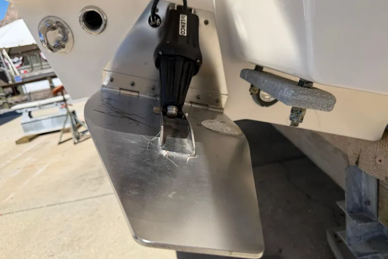 Slide: The Image of 2023 Robalo R360 Center Console trim tab detail in a boatyard setting. - 44