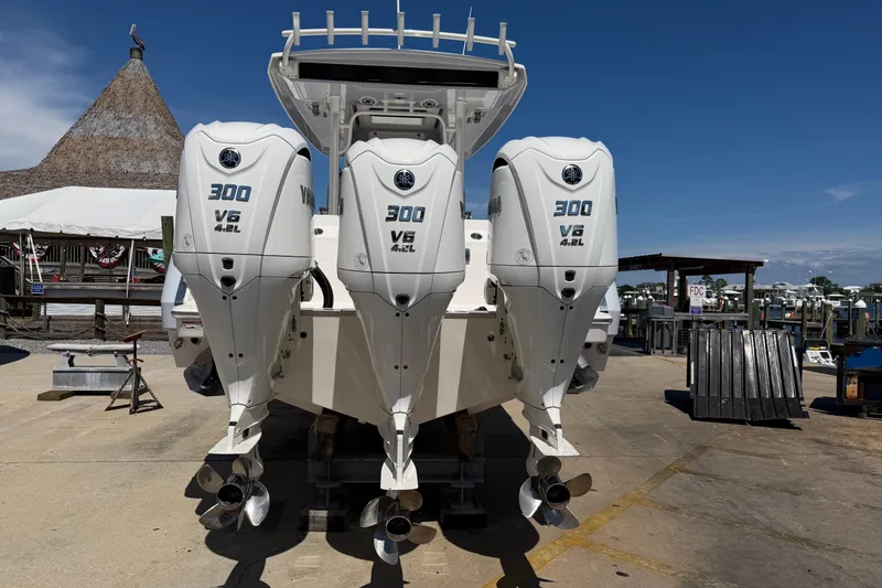 Slide: The Image of 2023 Robalo R360 Center Console with triple Yamaha 300 V6 engines at a marina. - 4