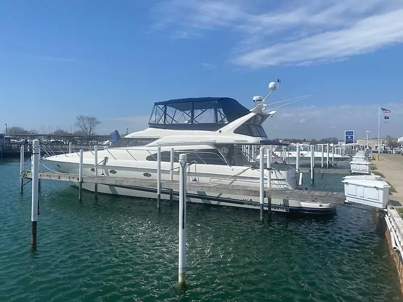 Slide: The Image of 1998 Sunseeker Manhattan 62 docked, featuring a blue canopy and calm waters. - 6