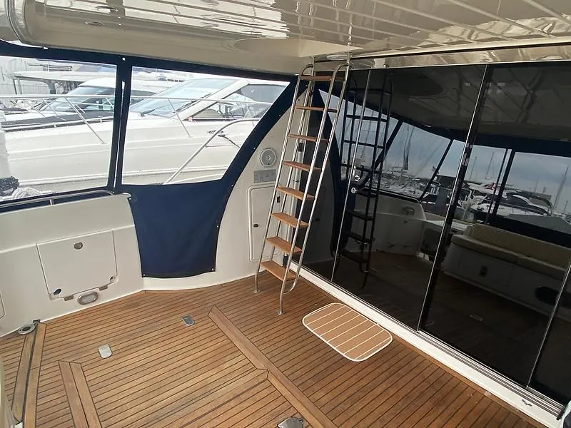 Slide: The Image of The image shows the teak deck of a 1998 Sunseeker Manhattan 62 with a ladder and glass walls. - 11
