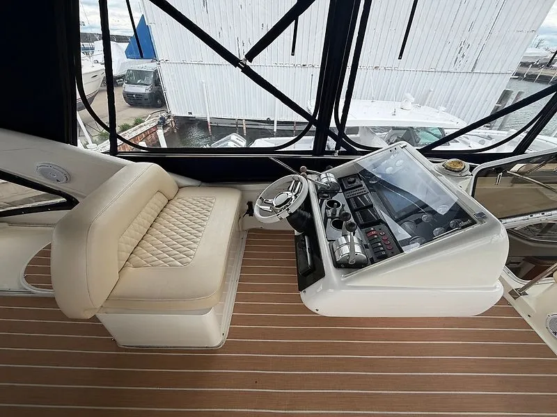 Slide: The Image of The image shows the cockpit of a 1998 Sunseeker Manhattan 62 with a cushioned seat and modern helm. - 13
