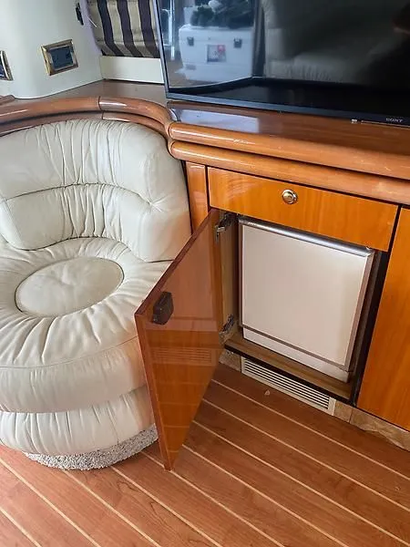 Slide: The Image of Interior of the 1998 Sunseeker Manhattan 62 with a beige leather chair and an open wooden cabinet. - 23