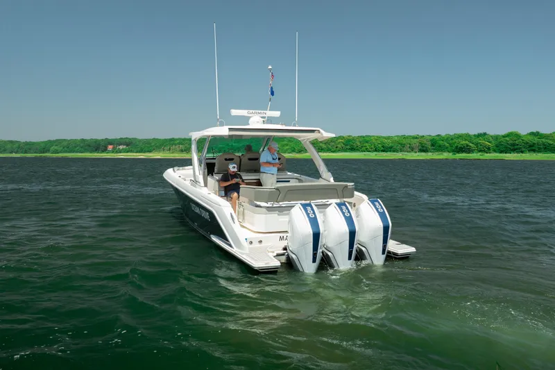 Slide: The Image of 2022 Tiara Yachts 38 LS cruising on a serene lake with lush green shoreline. - 4