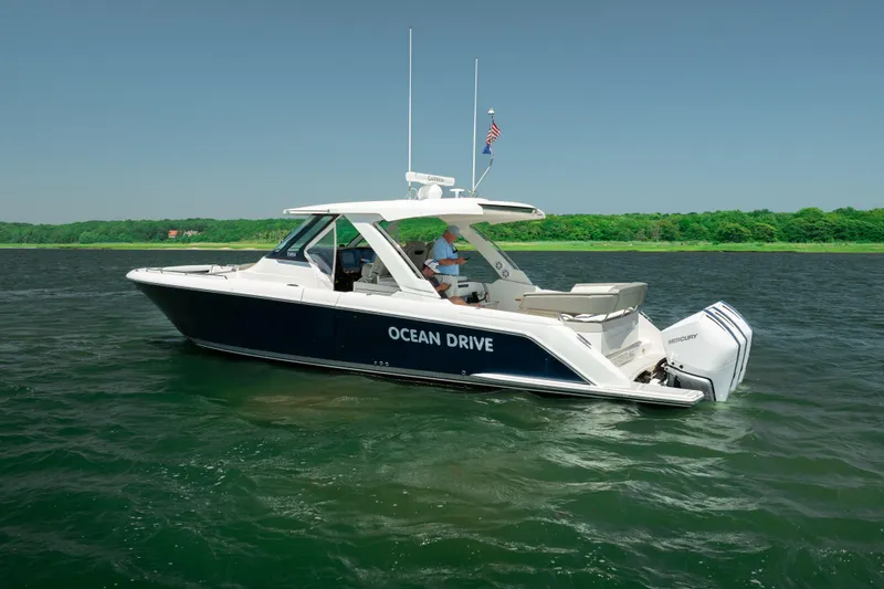 Slide: The Image of 2022 Tiara Yachts 38 LS cruising on a serene lake with lush green shoreline. - 8
