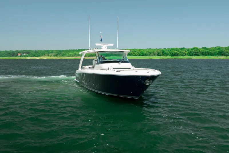 Slide: The Image of 2022 Tiara Yachts 38 LS cruising on a serene lake with lush green shoreline. - 11