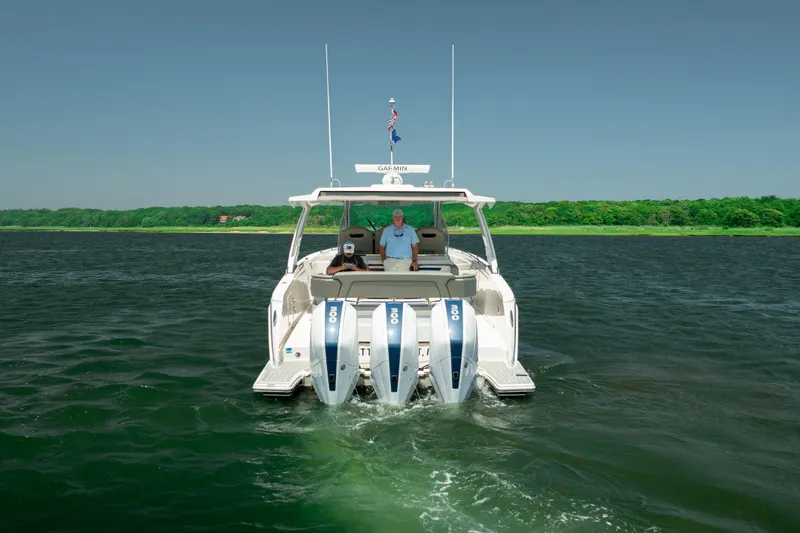 Slide: The Image of 2022 Tiara Yachts 38 LS cruising on a serene lake with lush green shoreline. - 3
