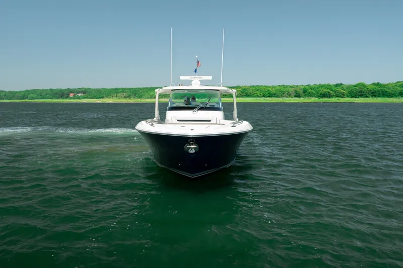 Slide: The Image of 2022 Tiara Yachts 38 LS cruising on a serene lake with lush green shoreline. - 10