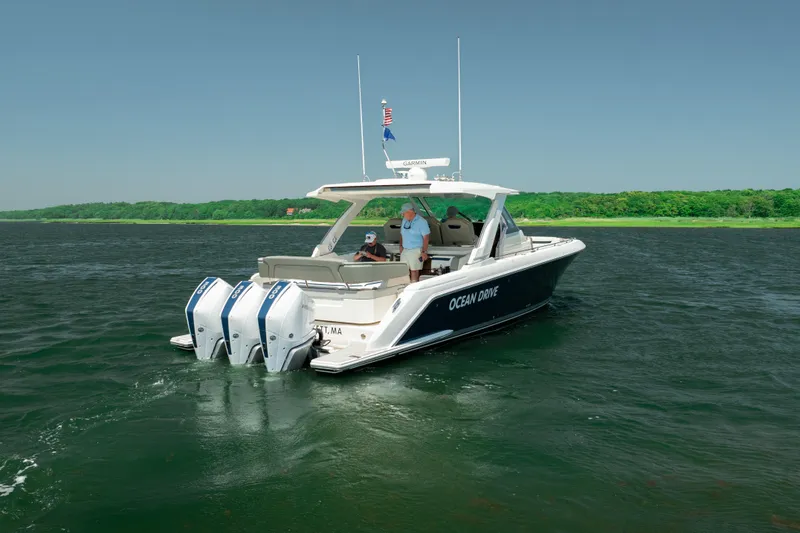 Slide: The Image of 2022 Tiara Yachts 38 LS cruising on a serene lake with lush green shoreline. - 1