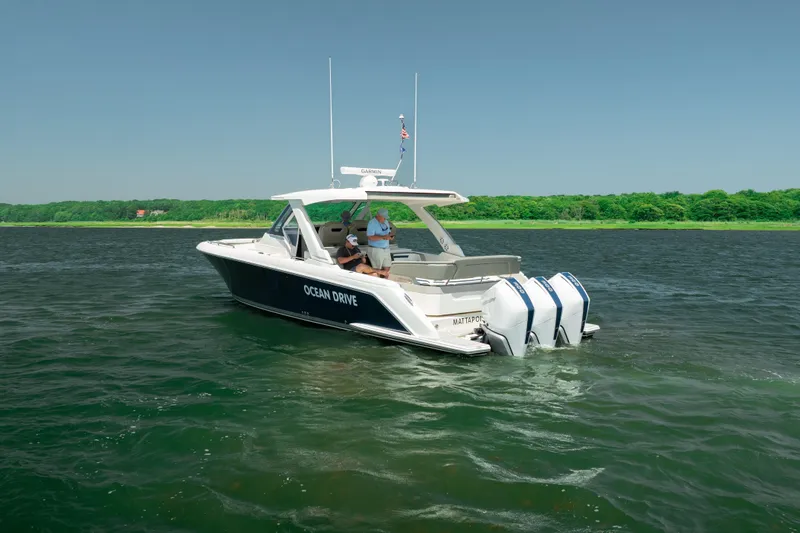 Slide: The Image of 2022 Tiara Yachts 38 LS cruising on a serene lake with lush green shoreline. - 9