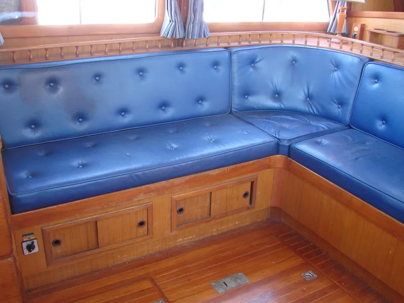 Slide: The Image of The interior view shows a blue upholstered corner bench with wooden flooring and windows in the background. - 7