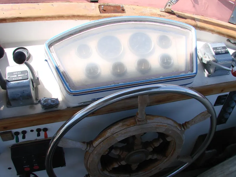Slide: The Image of The image shows the helm of a 1981 Kha Shing Sundeck ACMY with a wooden wheel and instruments. - 44