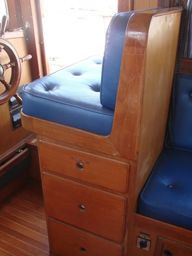 Slide: The Image of A wooden helm seat with blue upholstery and drawers underneath, inside a boat. - 8