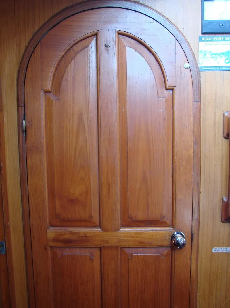 Slide: The Image of A wooden door with an arched design on a boat, surrounded by wood paneling. - 20