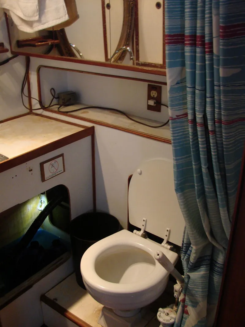 Slide: The Image of The image shows a boat bathroom with a toilet and a shower curtain. - 26