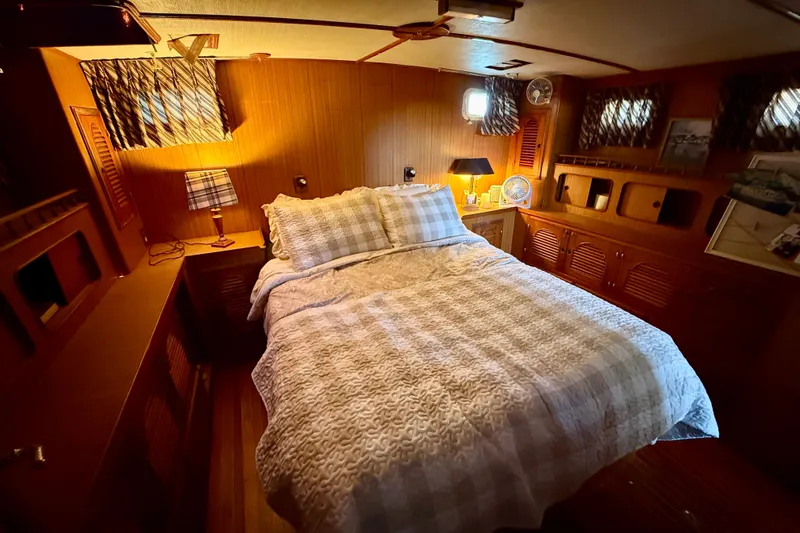 Slide: The Image of Cozy bedroom interior of 1981 Kha Shing Sundeck ACMY yacht with wood paneling and soft lighting. - 16