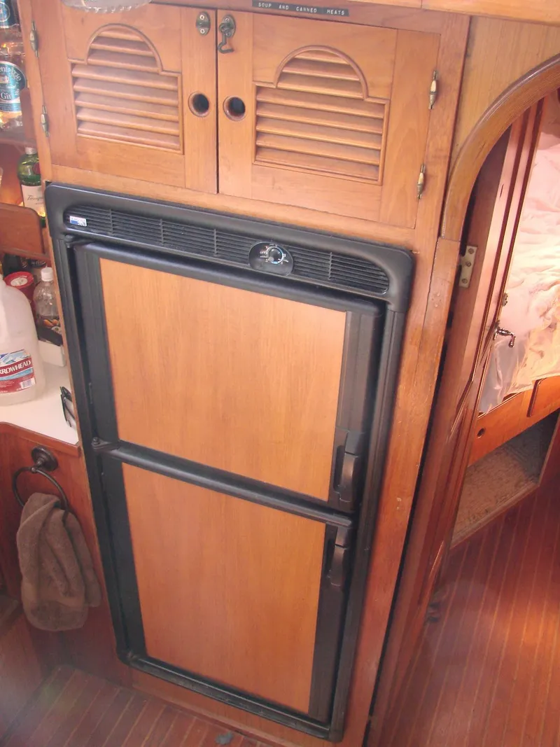 Slide: The Image of Interior of a yacht featuring a wooden refrigerator and cabinets, creating a cozy atmosphere. - 14