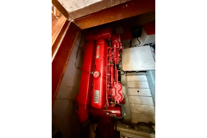 Slide: The Image of Engine compartment of 1981 Kha Shing Sundeck ACMY, featuring a red marine engine. - 54