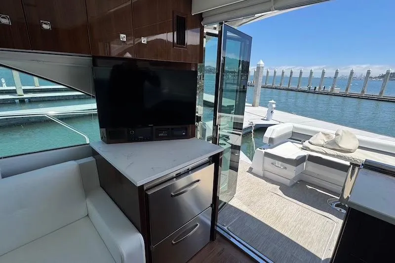 Slide: The Image of Interior of 2023 Cruisers Yachts 50 Cantius with TV, seating, and marina view. - 17