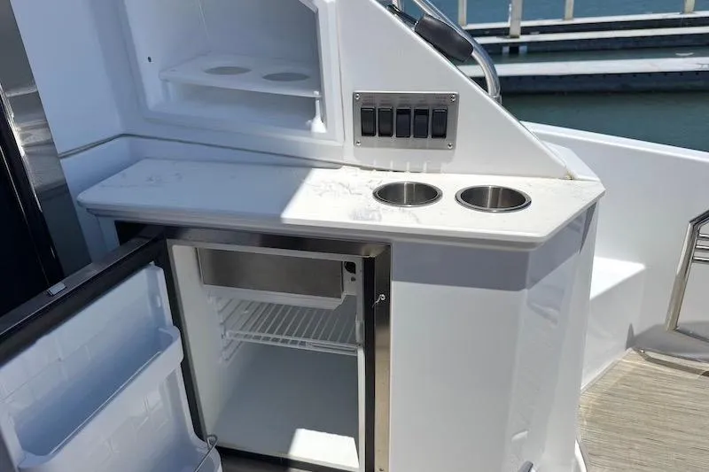 Slide: The Image of Open mini fridge and cup holders on 2023 Cruisers Yachts 50 Cantius deck. - 11