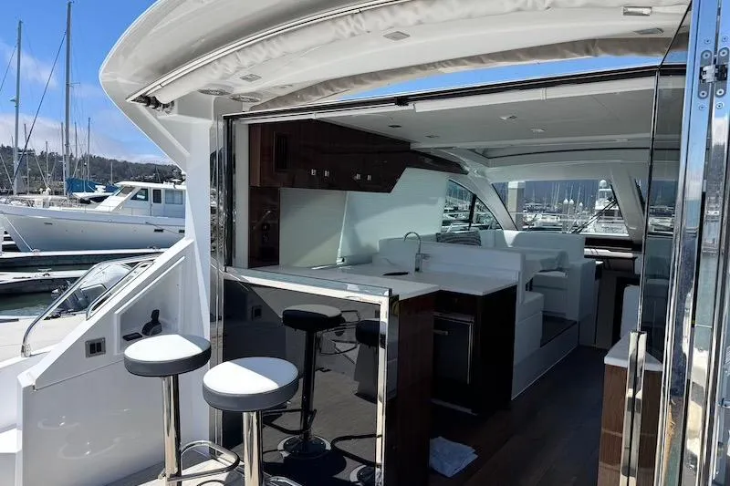 Slide: The Image of 2023 Cruisers Yachts 50 Cantius interior with modern kitchen and bar stools at marina. - 9