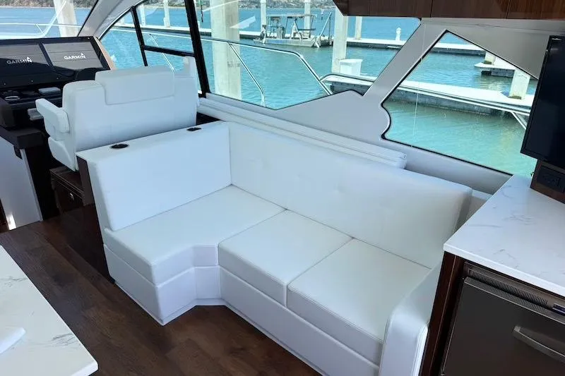 Slide: The Image of Luxurious interior of 2023 Cruisers Yachts 50 Cantius with white seating and scenic marina view. - 24