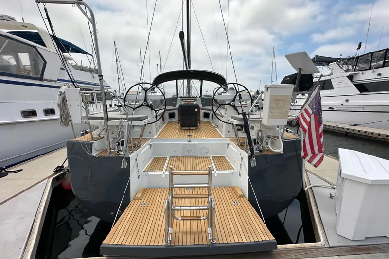 Slide: The Image of 2018 Jeanneau 54 yacht docked, featuring dual steering wheels and teak deck. - 20