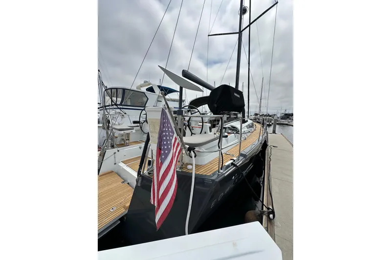 Slide: The Image of 2018 Jeanneau 54 yacht docked with American flag, showcasing sleek design and spacious deck. - 21