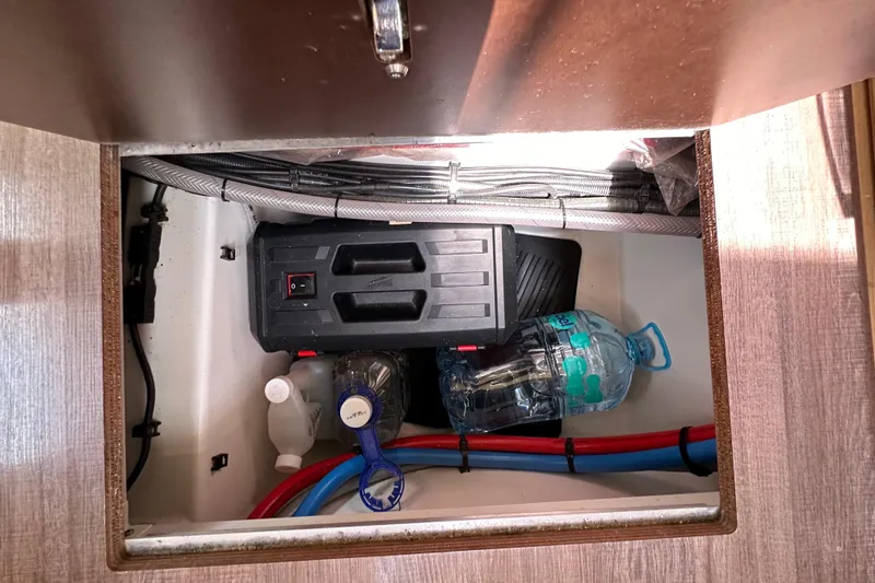 Slide: The Image of Storage compartment in a 2018 Jeanneau 54 yacht with cables and water bottles. - 116