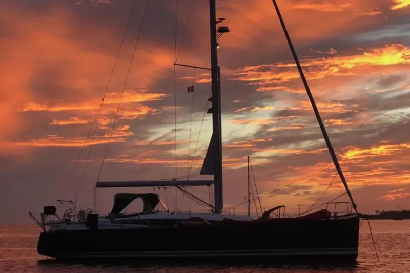 Slide: The Image of 2018 Jeanneau 54 sailboat silhouetted against a vibrant sunset sky. - 117