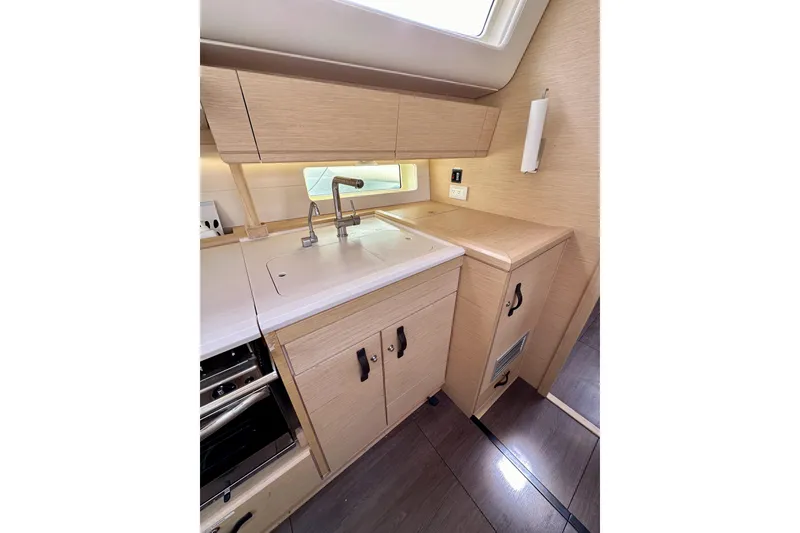 Slide: The Image of Modern kitchen area in a 2018 Jeanneau 54 yacht, featuring sleek cabinetry and a compact sink. - 94