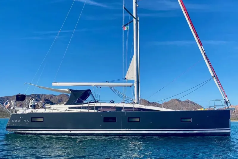 Slide: The Image of 2018 Jeanneau 54 sailboat on calm water with mountainous backdrop. - 3