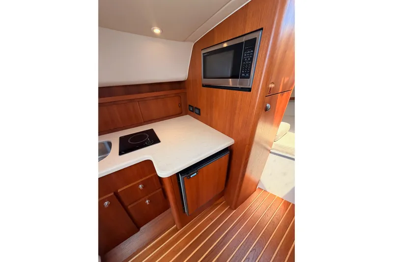 Slide: The Image of 2005 Tiara Yachts 2900 Open Classic galley with microwave, cooktop, and wood cabinetry. - 47