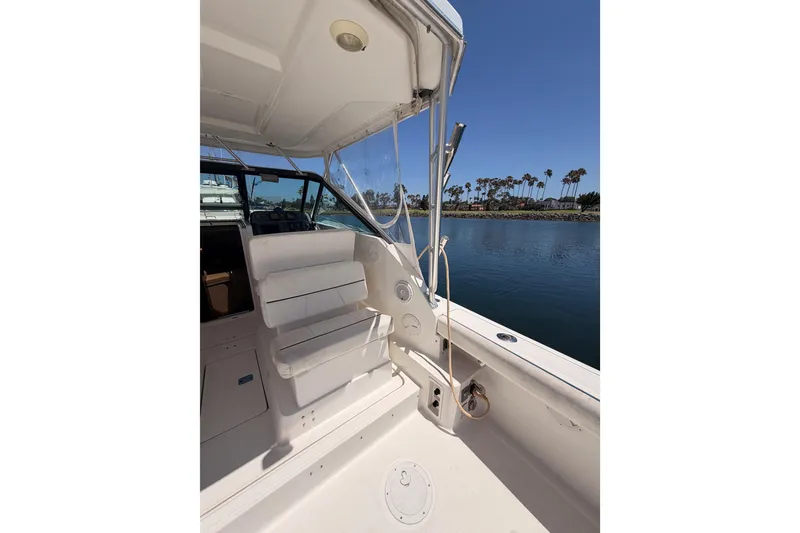 Slide: The Image of 2005 Tiara Yachts 2900 Open Classic boat interior with seating, docked by palm trees. - 13
