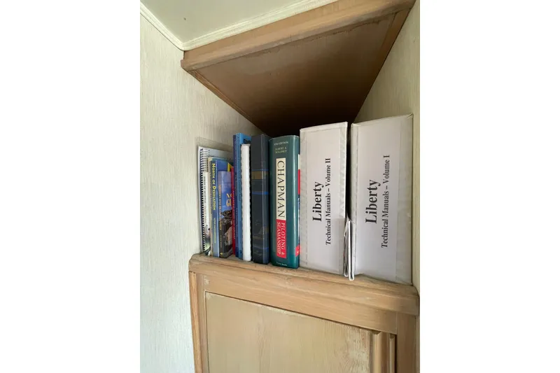 Slide: The Image of Books and manuals on a wooden shelf inside a 1990 Tollycraft 34 Sport Sedan. - 20