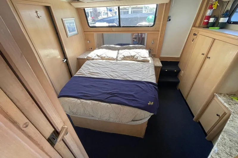 Slide: The Image of Cozy bedroom in 1990 Tollycraft 34 Sport Sedan yacht with wood cabinetry and large window. - 7
