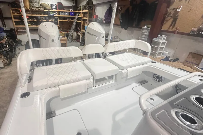 Slide: The Image of 2022 Costa Custom Boats 264HC interior with white seating and dual Mercury engines in a garage. - 12