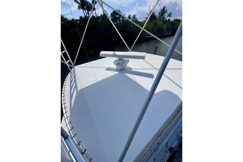 Slide: The Image of 1986 Bertram 46III Convertible yacht deck with radar, surrounded by lush greenery. - 34