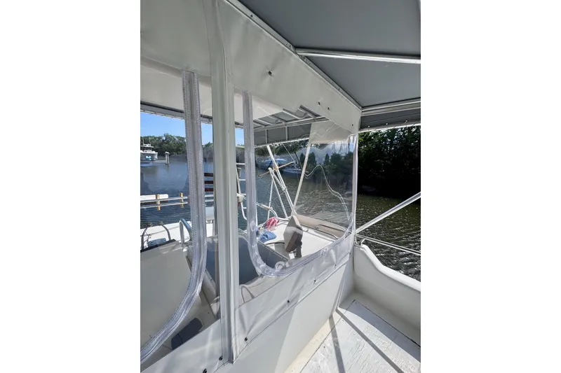 Slide: The Image of 1986 Bertram 46III Convertible boat interior with clear enclosure, docked by a river. - 33
