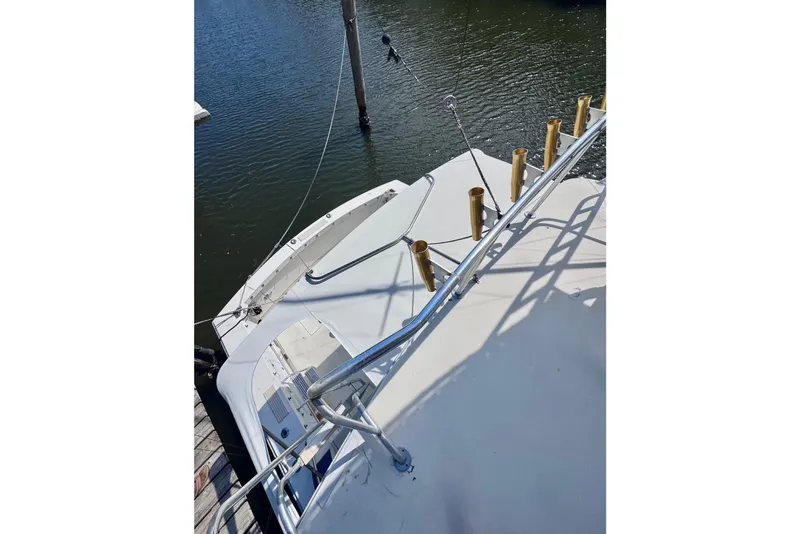 Slide: The Image of 1986 Bertram 46III Convertible yacht docked, featuring a spacious deck and fishing rod holders. - 23